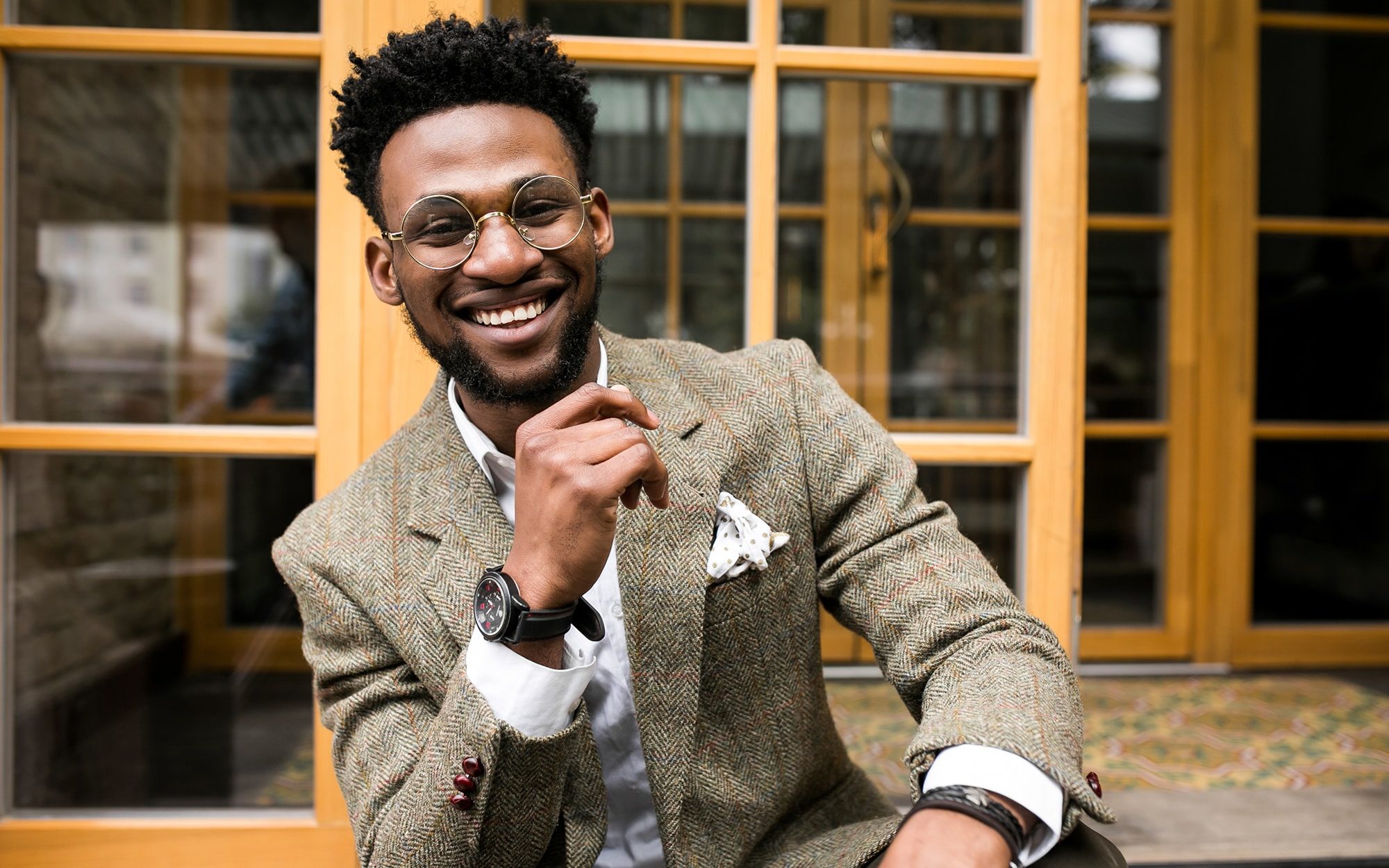 Male model wearing a costume with fake glasses and heavy tweed coat smiling