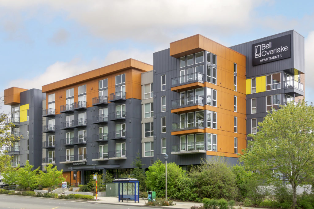 exterior building with balconies, bus stop in front